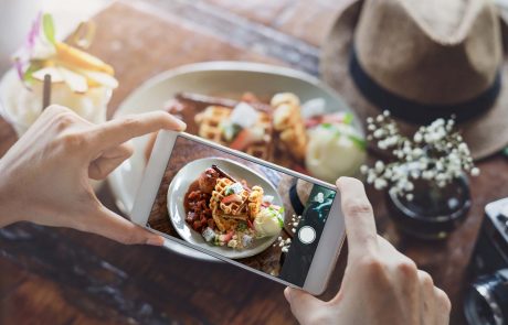 Young woman taking photo of food with smart phone in restaurant
