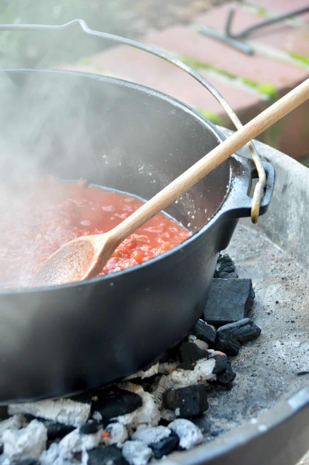 Tomatensuppe zubereiten auf Holzkohle Tomaten andünsten Im gusseisernen Topf auf Holzkohlenfeuer