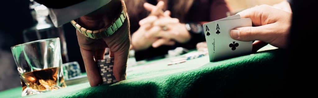 Poker Kartenspieler am Spieltisch mit Jetons und Karten und Whisky