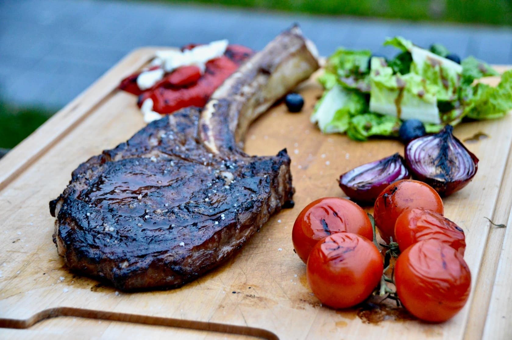 Wagyu-Tomahawk-Steak gegrillt mit Tomaten und Salat Wagyu Tomahawk Steak gegrillt mit Tomaten und Salat