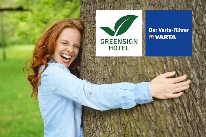 lachende frau umarmt einen großen baum im wald