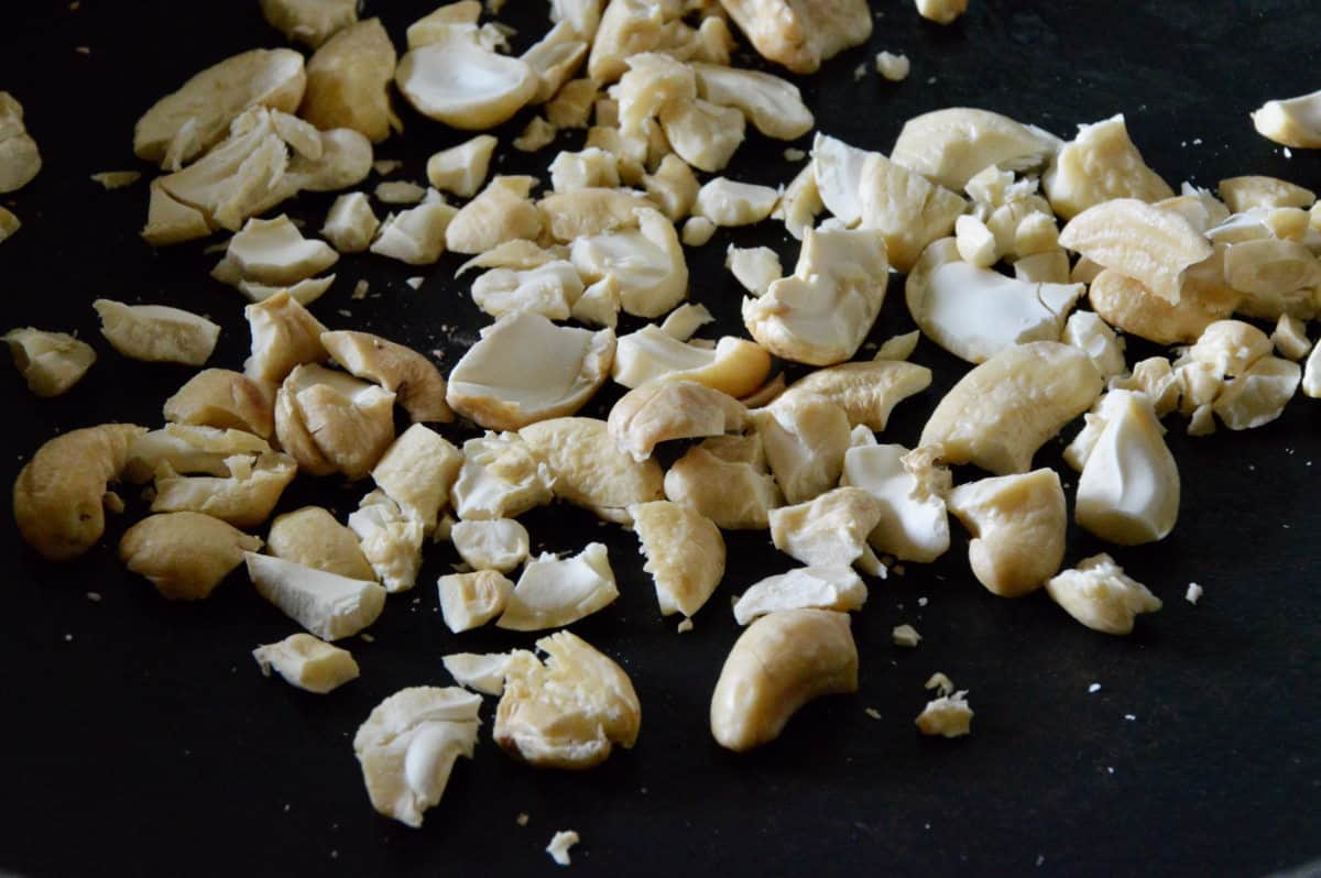 cashew-kerne Zerstoßene Cashew-Kerne auf schwarzem Hintergrund