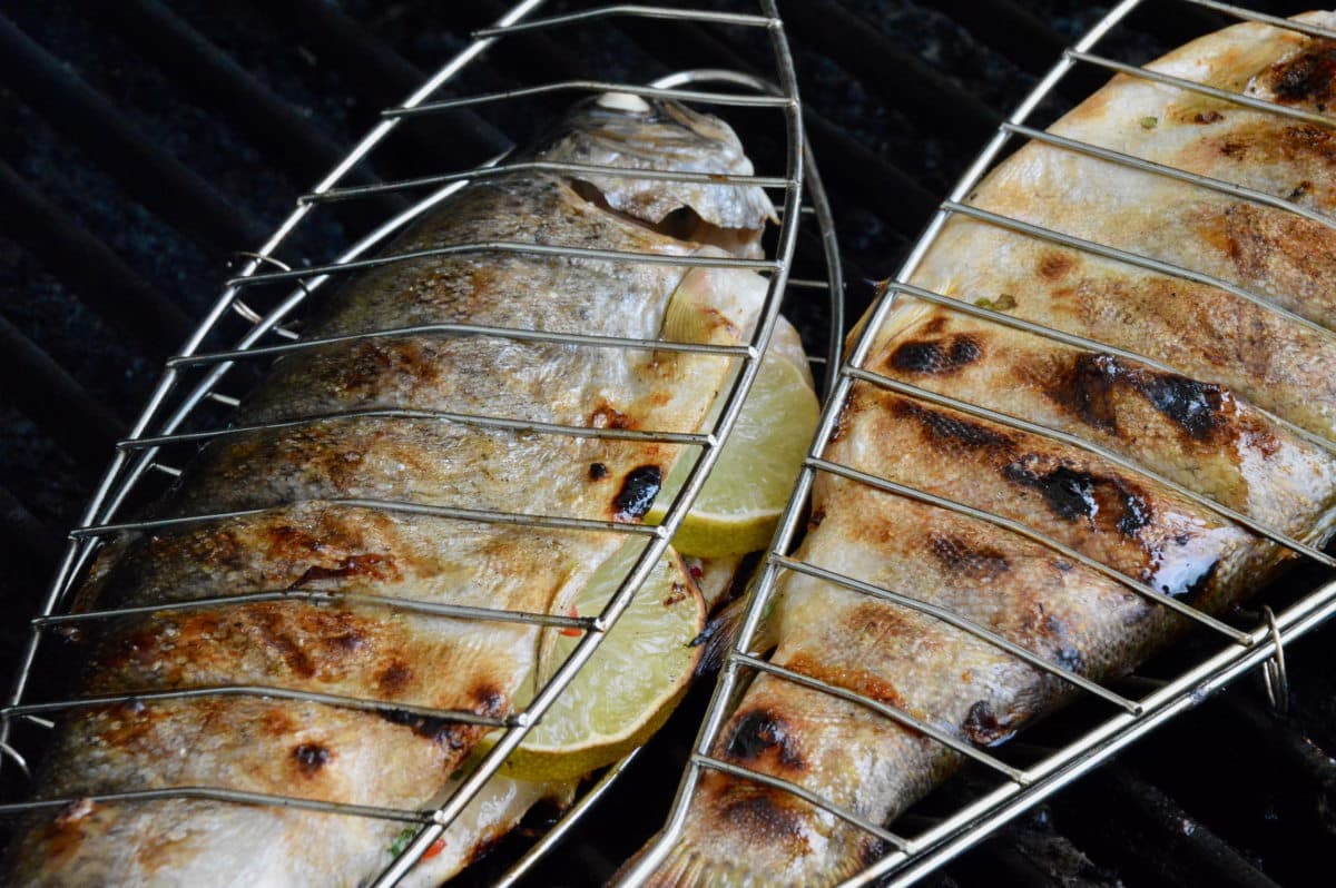 Forellen auf dem Grill 2 Forellen im Fischhalter auf dem Grill
