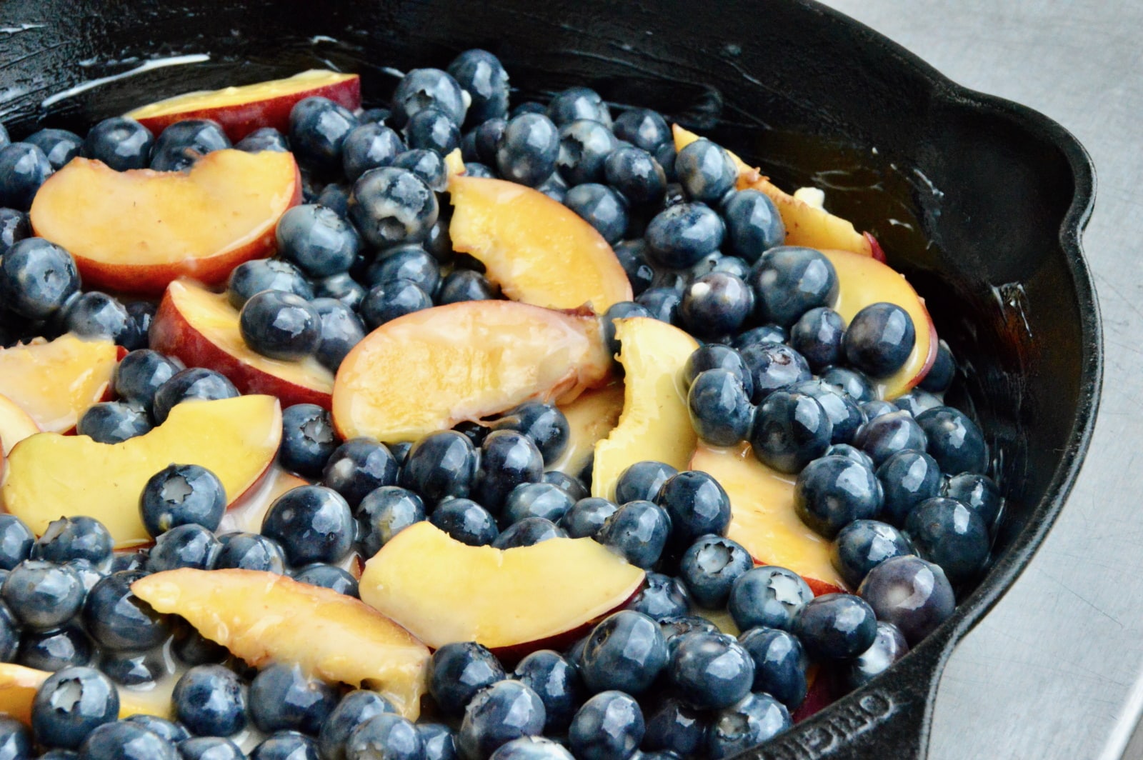 Cobbler mit Blaubeeren und Nektarinen Blaubeeren und Nektarinen in einer Gusspfanne