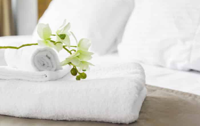 weiße Handtücher mit Orchidee auf einem Hotelbett