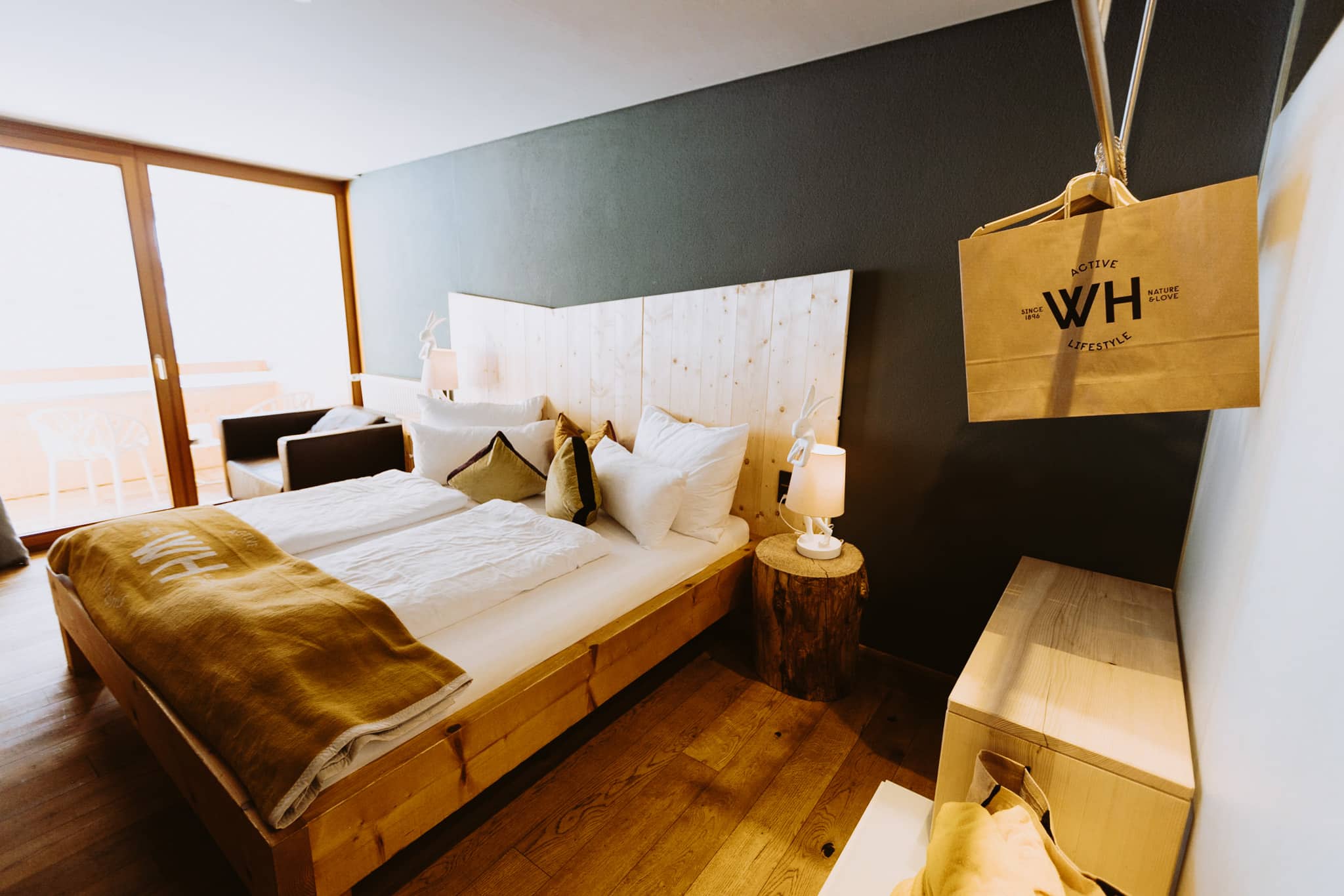 Zimmer alpinista -4 Zimmeransicht Hotel Walliserhof mit Holzdielen und Holzbett und Kommode und Balkon
