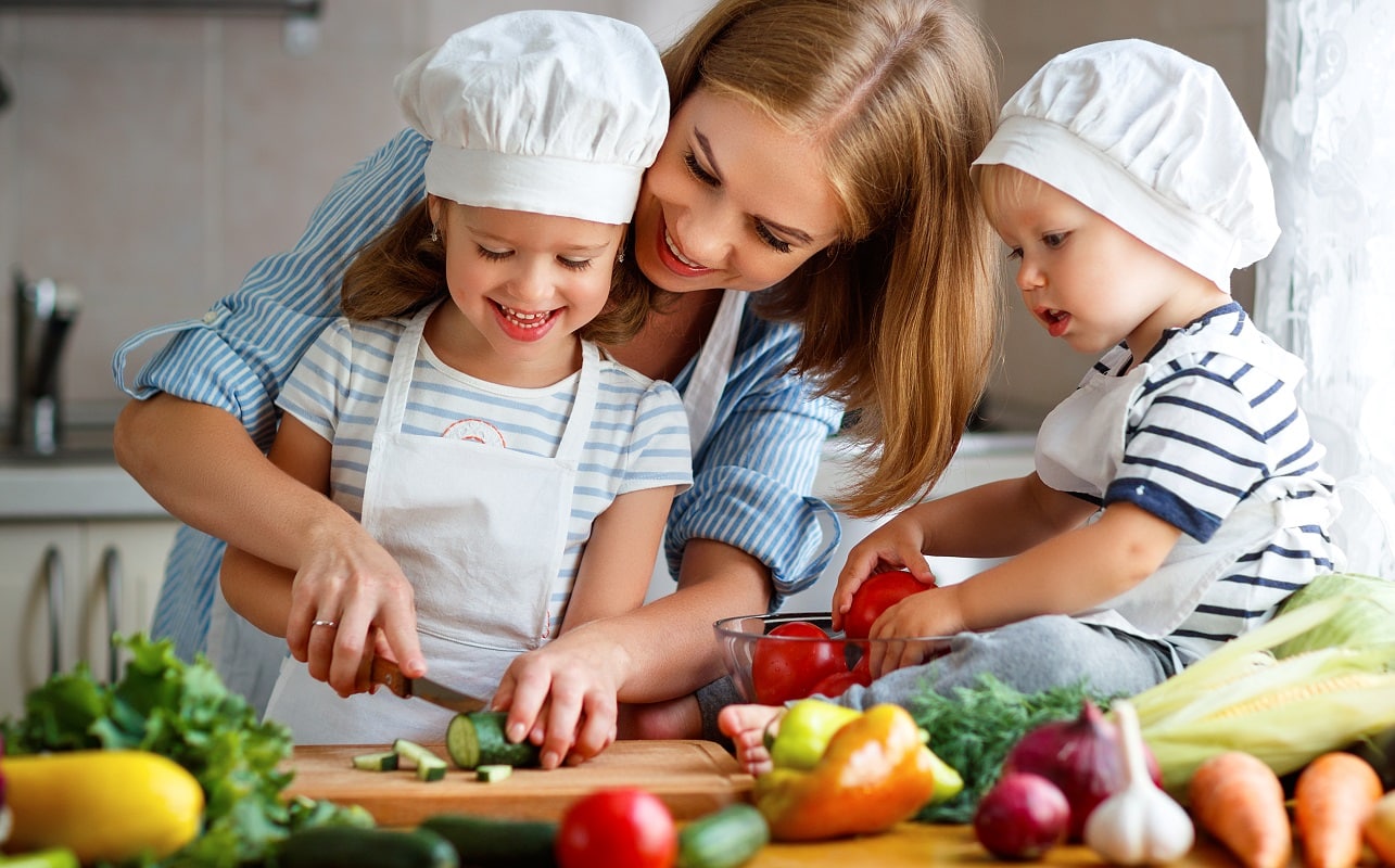 Kind beim Schnippeln mit Mamas Hilfe - Kochen mit Kindern