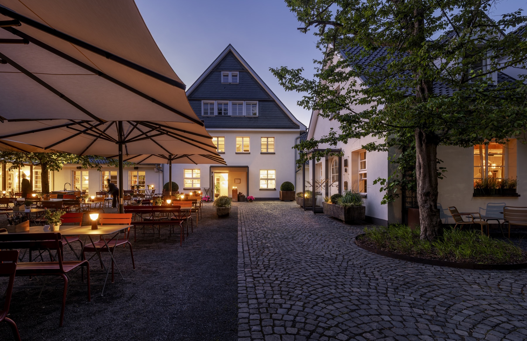 2026_Diepeschrather Mühle MÜLLERS -Schote aussen Abendaufnahme Innhof mit Restaurantterrasse in der Diepeschrather Mühle