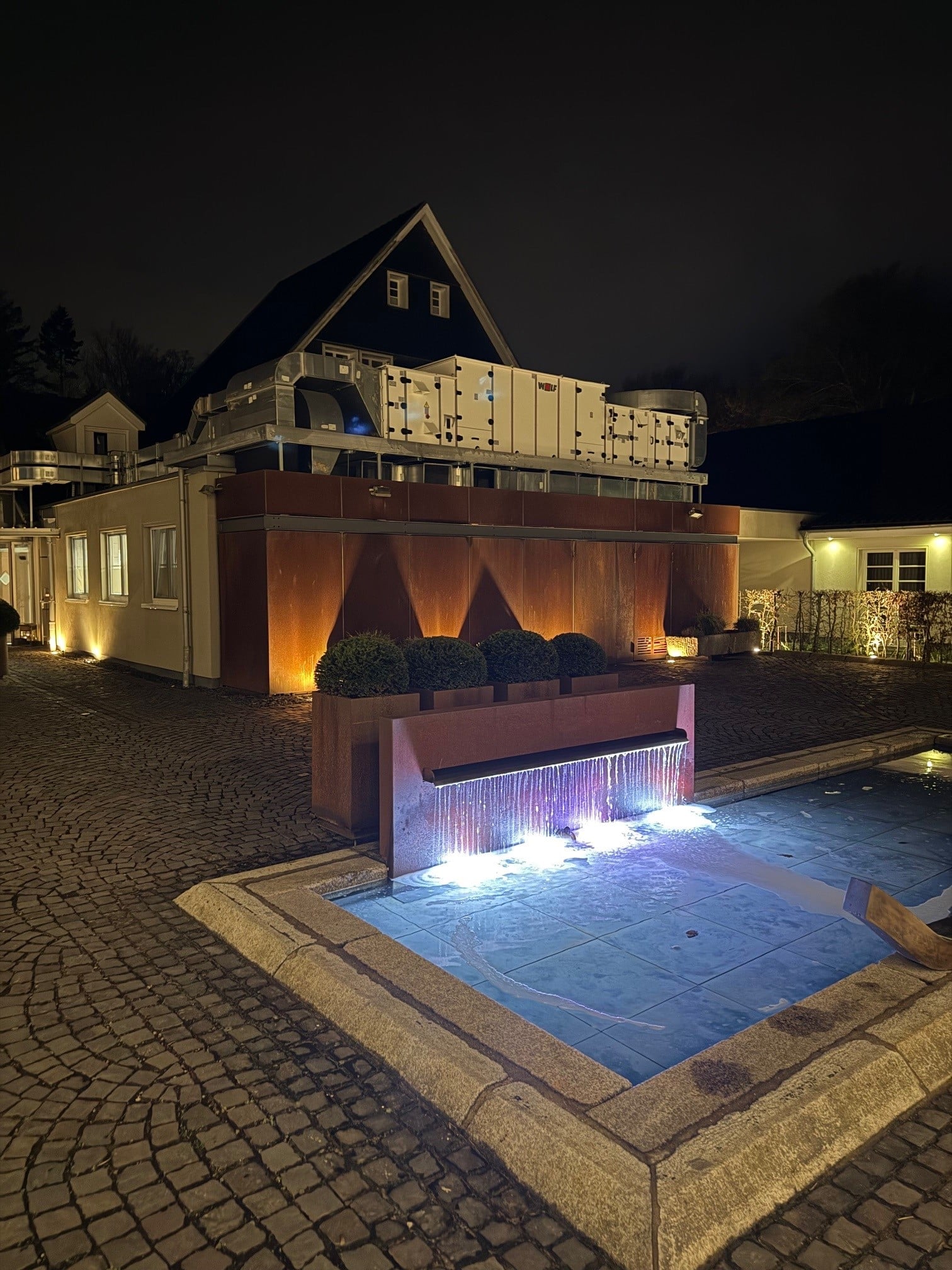Außenansicht_abends Blick auf die Diepeschrather Mühle mit beleuchtetem Pool bei Nacht