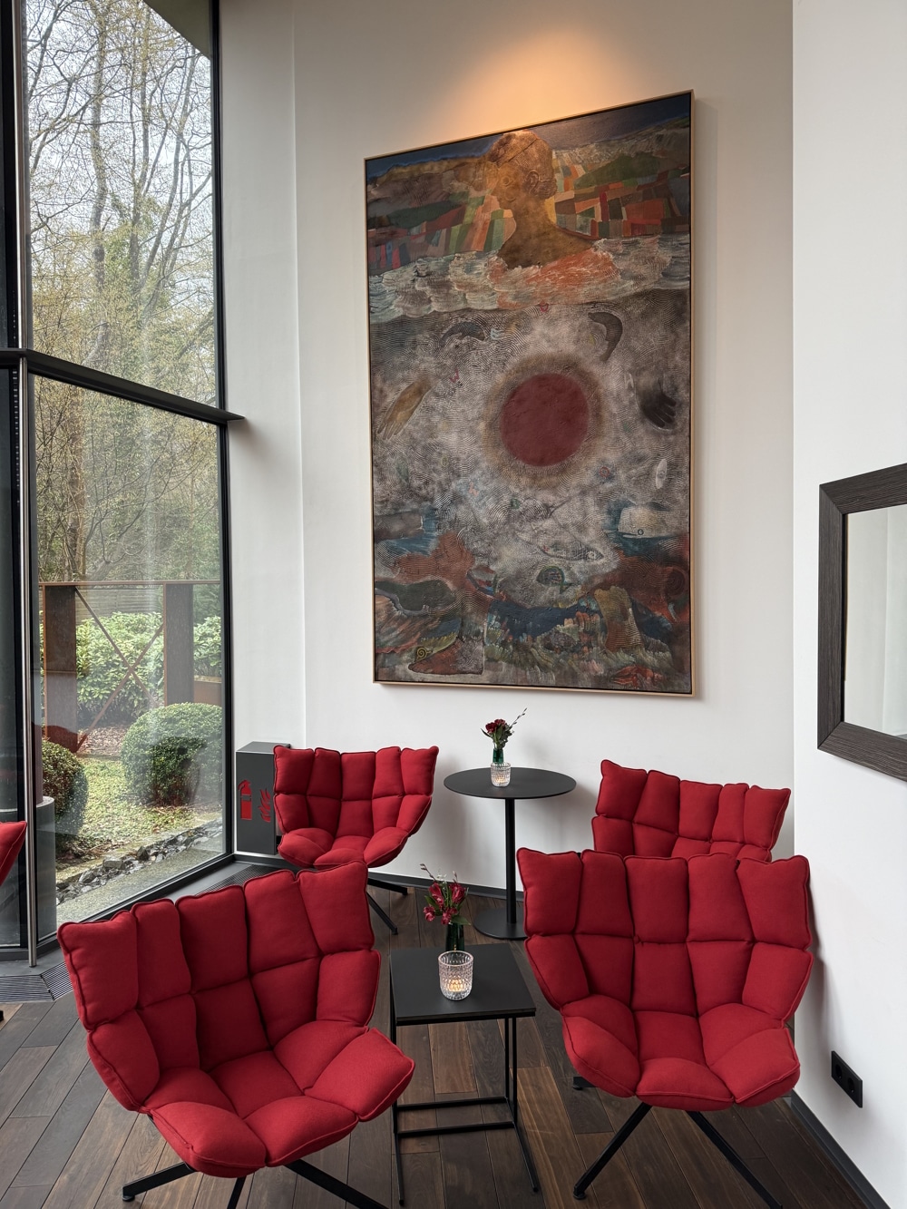 Lobby – Diepeschrather Mühle Lobby mit roten Designersesseln vor großen Bild und bodentiefer Fensterfront