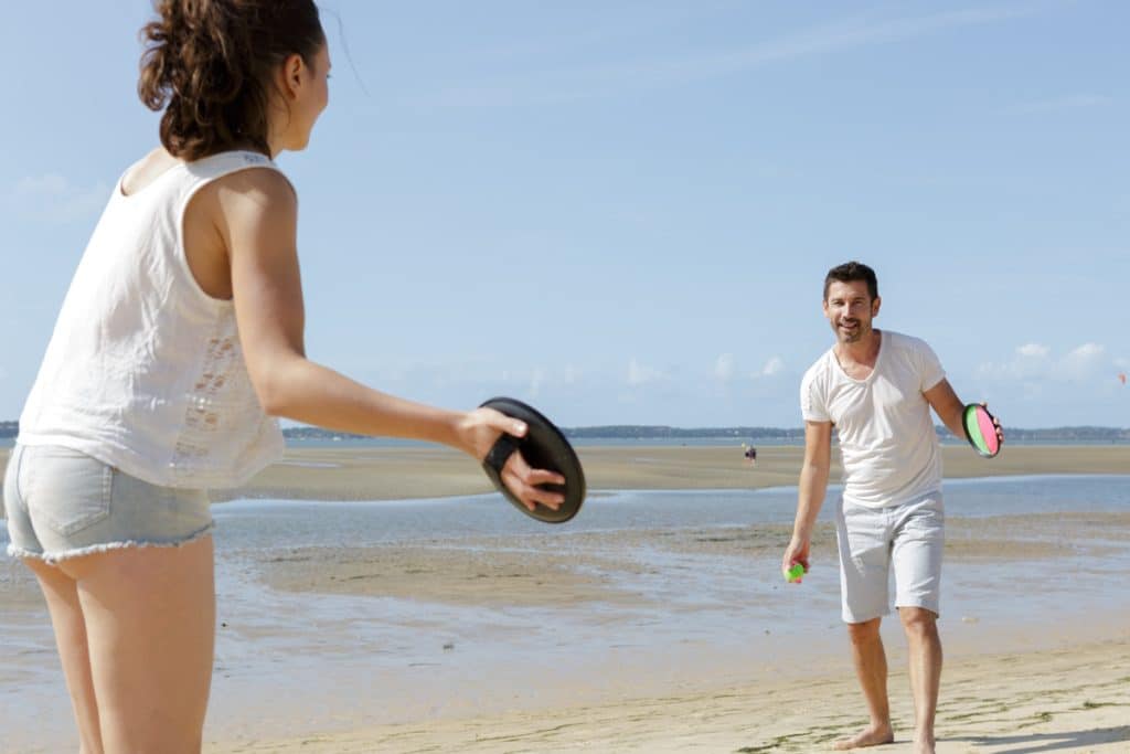 active couple playing ball game on the beach Pärchen am Strand spielt Klettball
