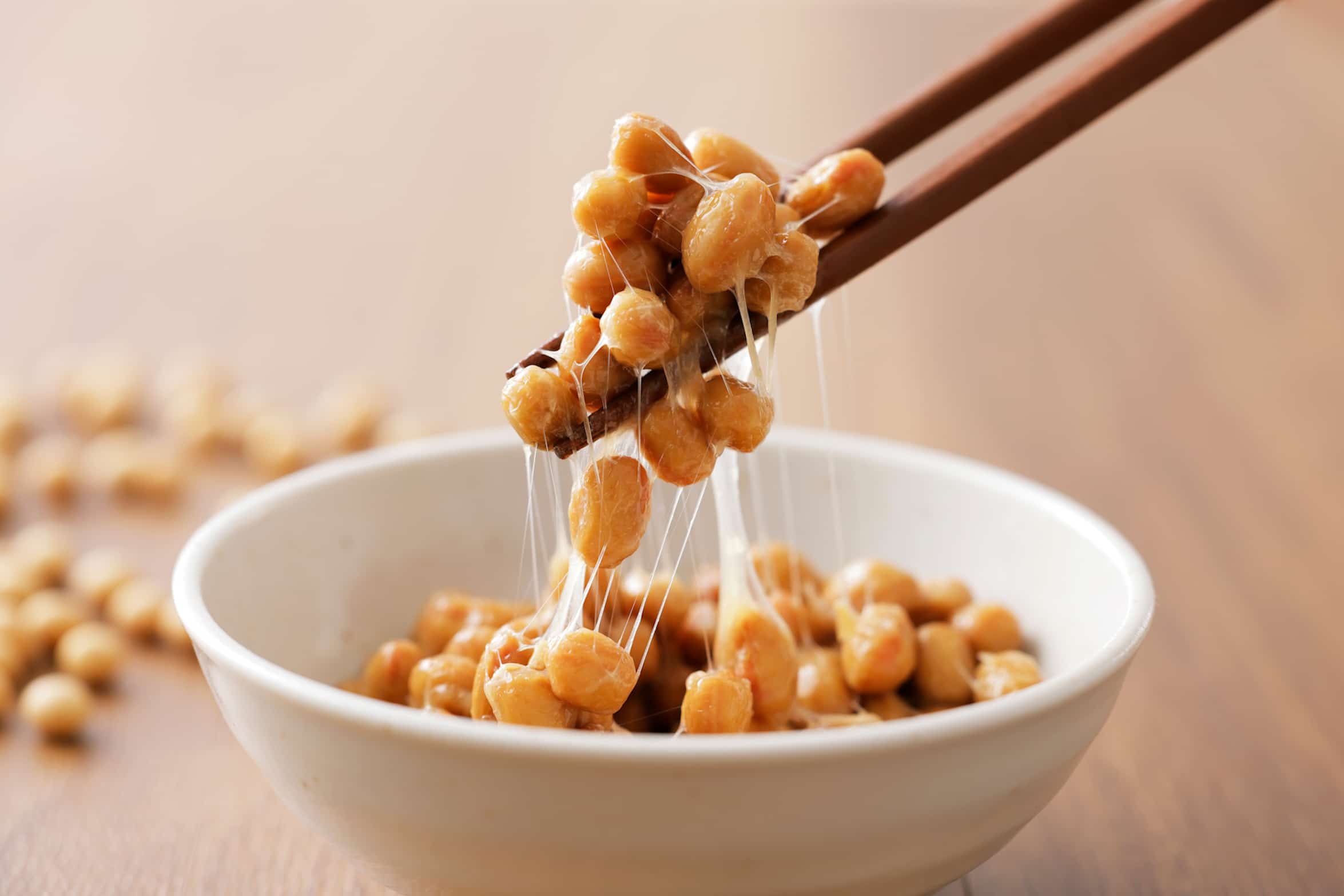 Natto Gericht aus Japan mit fermentierten Sojabohnen, die beim Aufnehmen mit Stäbchen lange Fäden ziehen