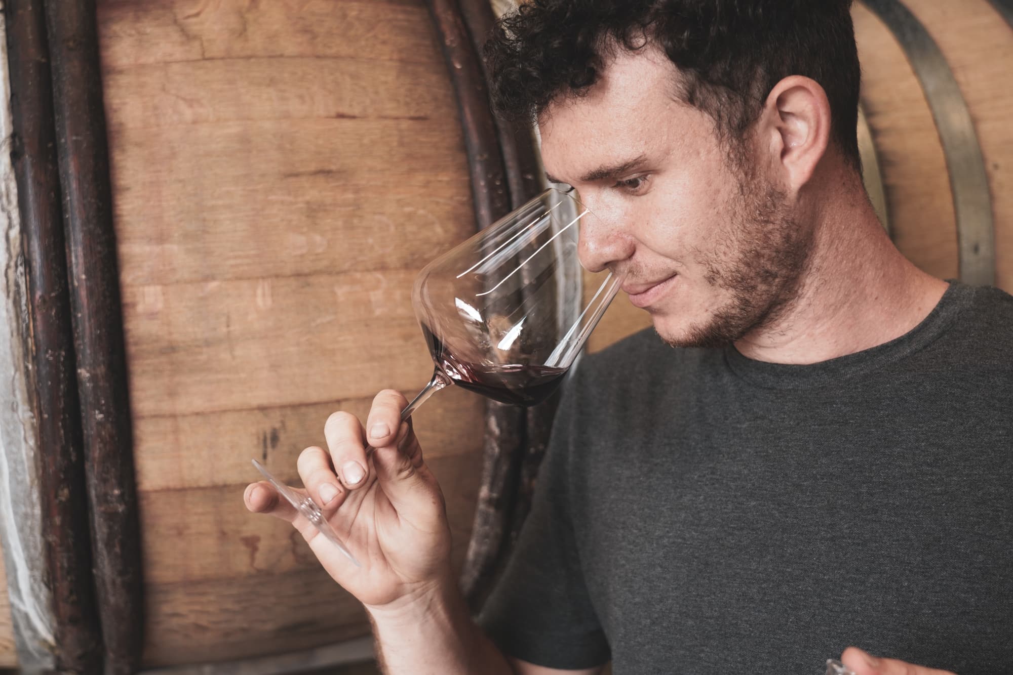 Portrait Jonas Kurek bei der Weinprobe vor großem Holzfass