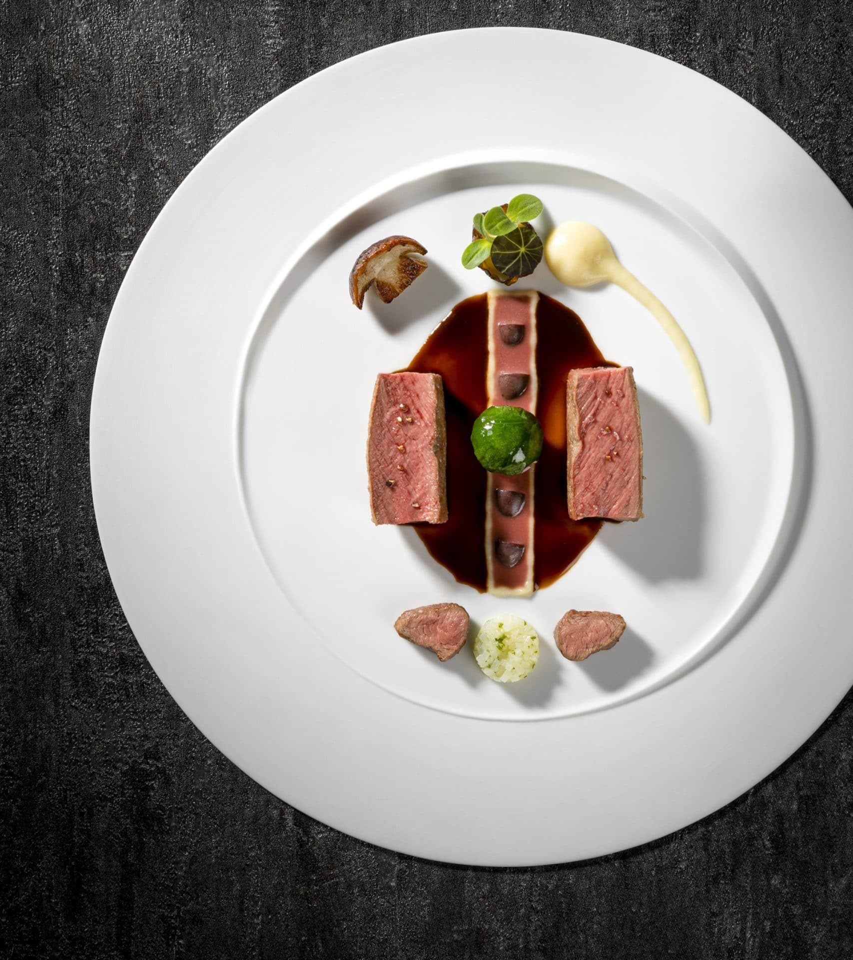 Modern interpretierter Rehrücken, präzise angerichtet mit feinen Komponenten und Jus.