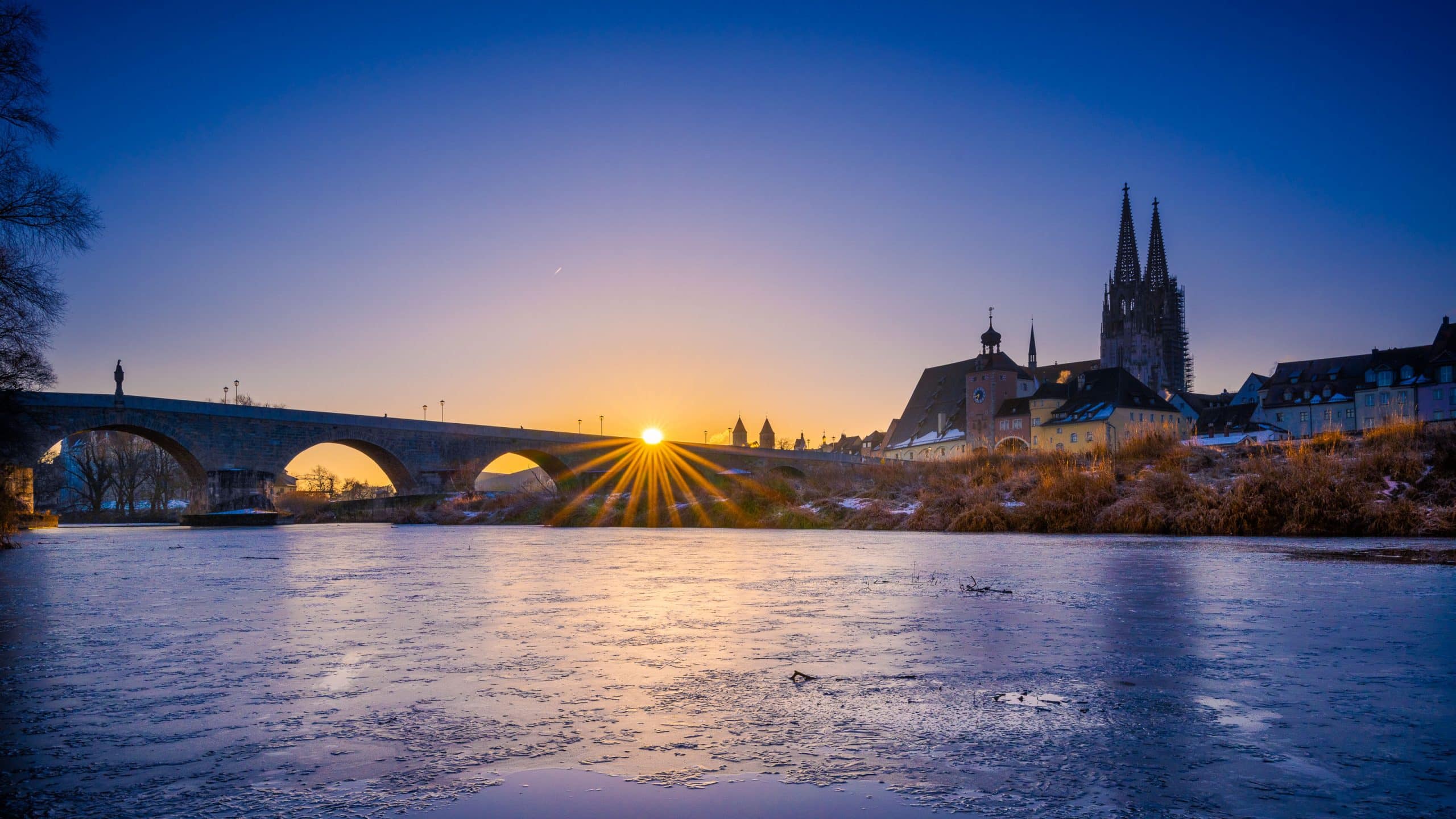 Sunrise over Stone Bridge in Regensburg, Bavaria, Germany in winter with frozen Danube Sonnenaufgang über der Steinernen Brücke in Regensburg