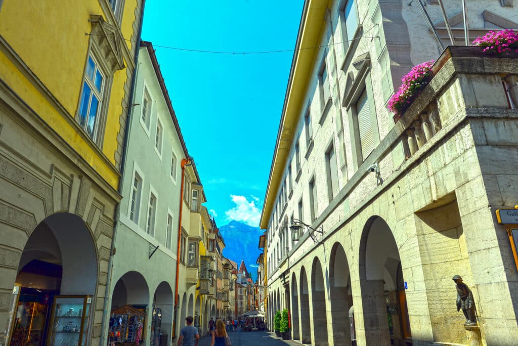 Laubengasse Meran Gasse mit Laubengängen in Merans Altstadt im Sommer mit Blick auf Berggipfel