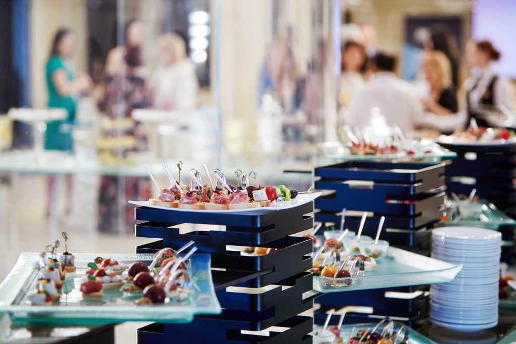 Conference banquet table Banquet table covered with trays with canapes with people standing in the background