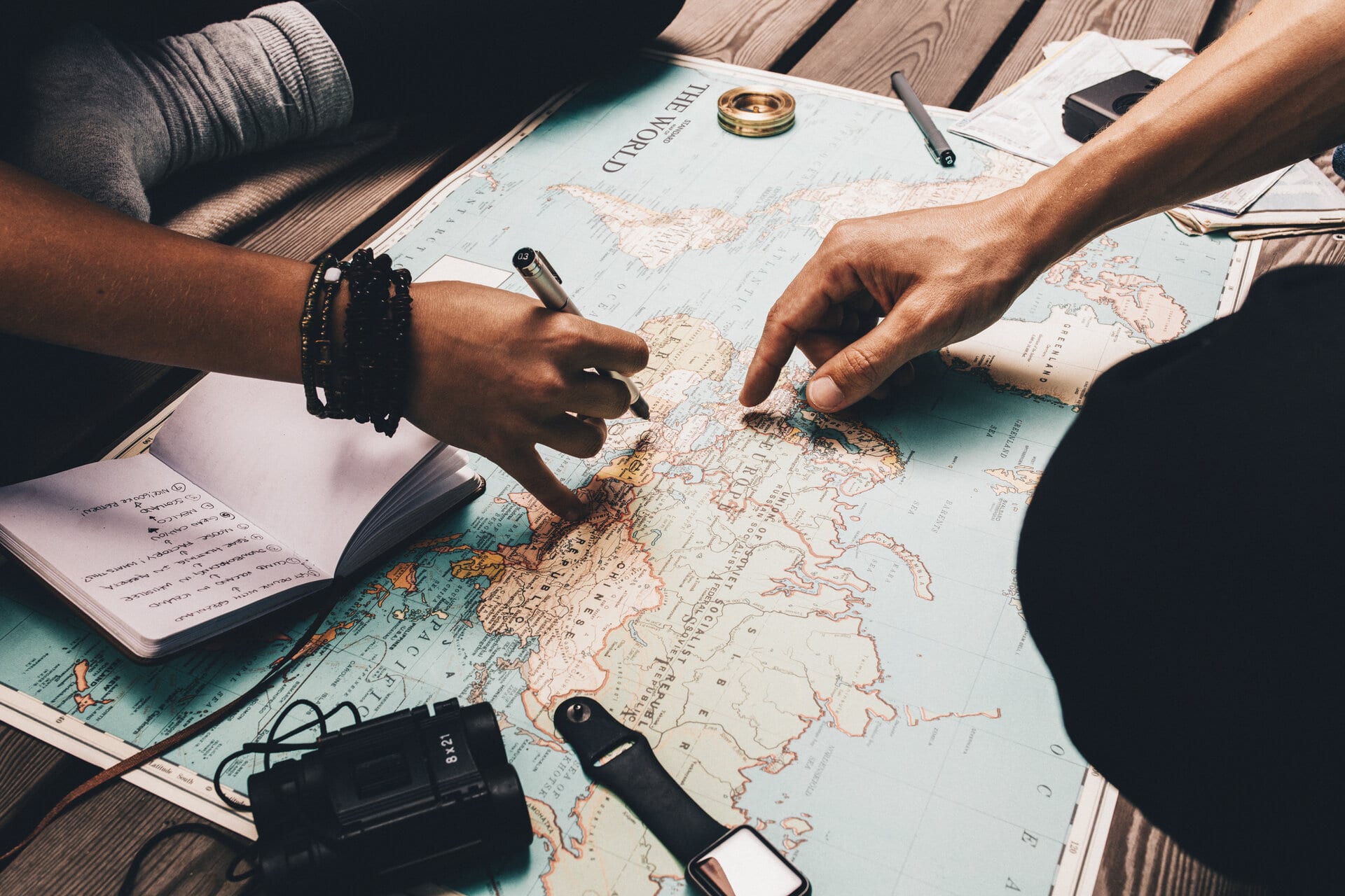 Couple planning vacation using the world map. Paar sitzt vor einer Weltkarte und plant eine Reise