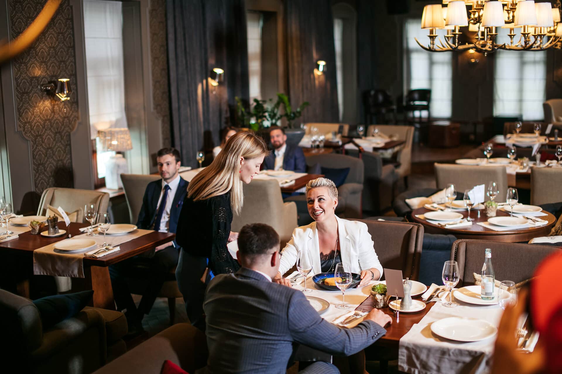 Friends Enjoying Meal Restaurant Gäste im Restaurant. ein Paar wird von einer Kellnerin bedientt 2 änner sitzen allein am Tisch