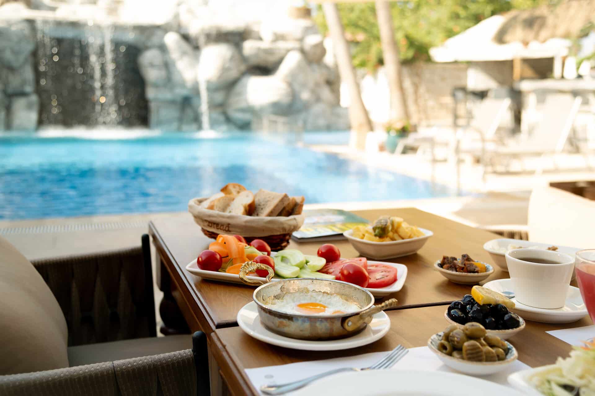 Omelette and Bread by the Poolside Breakfast Frühstück mit Omelette, Früchten, Gemüse auf einem Tisch am Pool