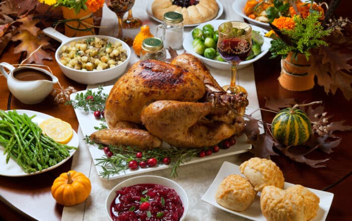 Thanksgiving Menü mit Truthahn und Beilagen, Soße, Rosenkohl, grüner Spargel, Preiselbeeren etc. auf einem Tisch