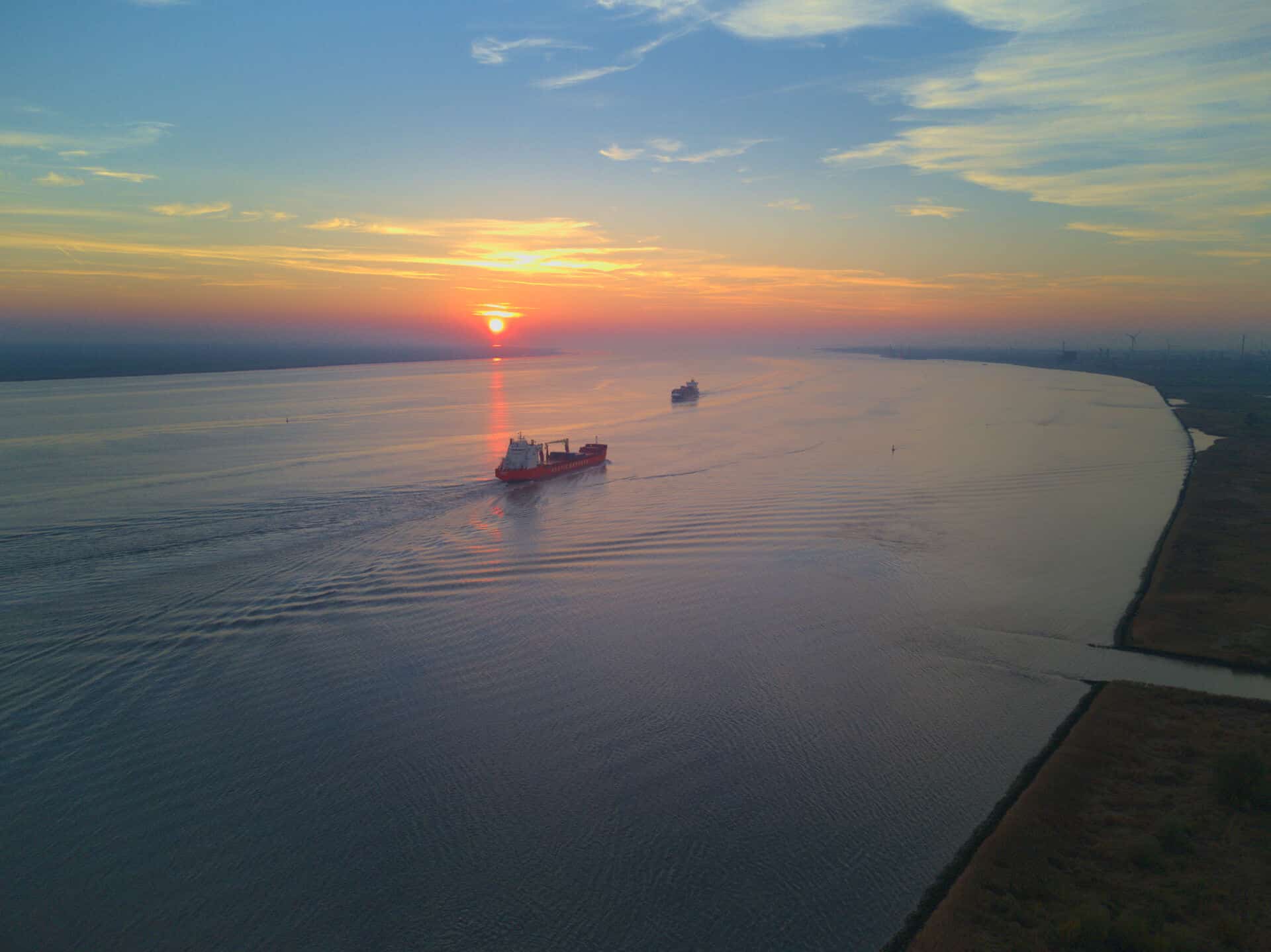 Schiff auf der Elbe fährt bei Sonnenuntergang in die Nordsee