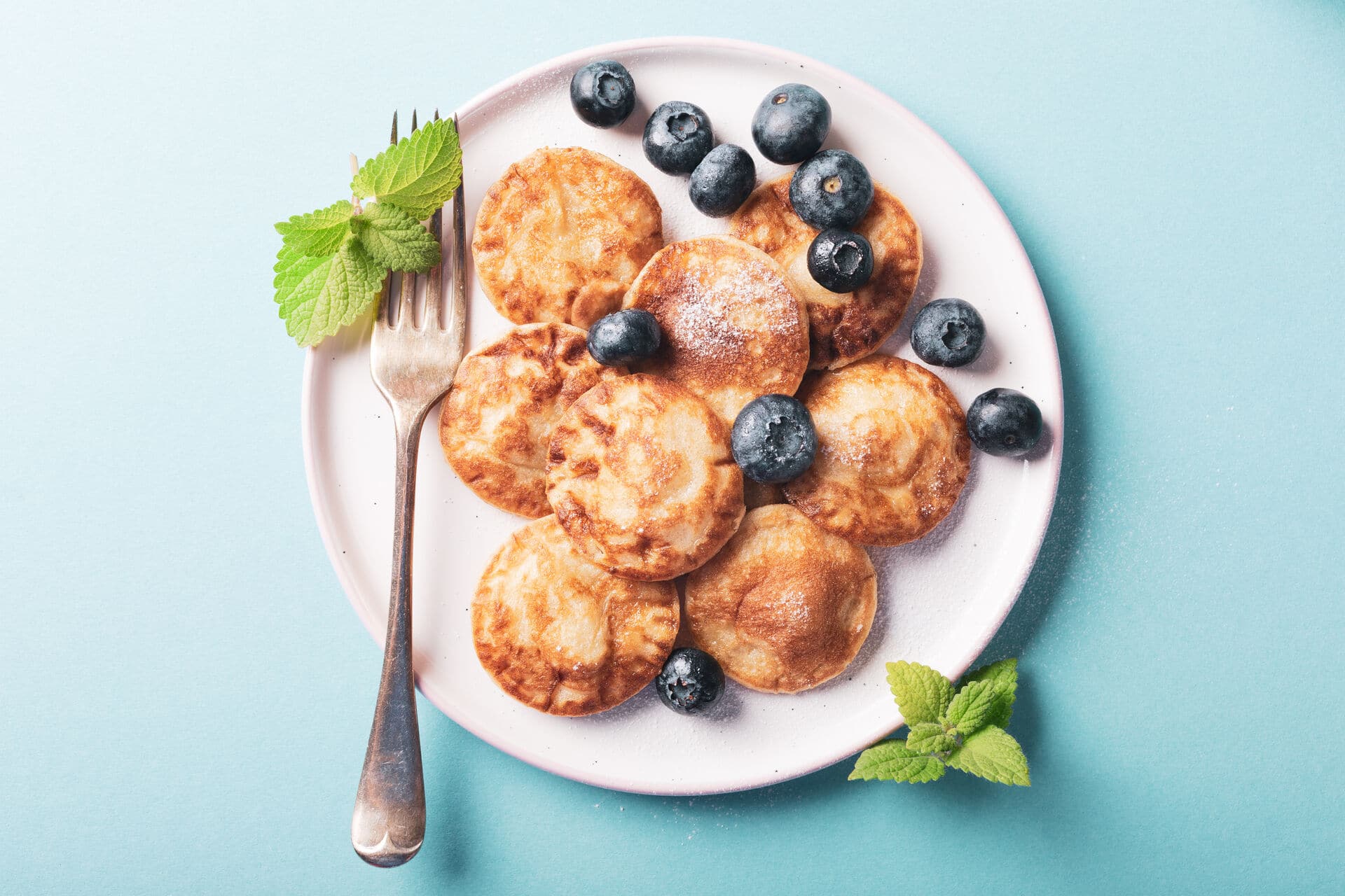 Poffertjes – Dutch mini pancakes Overhead shoot of dutch mini pancakes called poffertjes with blueberries, sprinkled with powdered sugar. Healthy food concept with copy space.